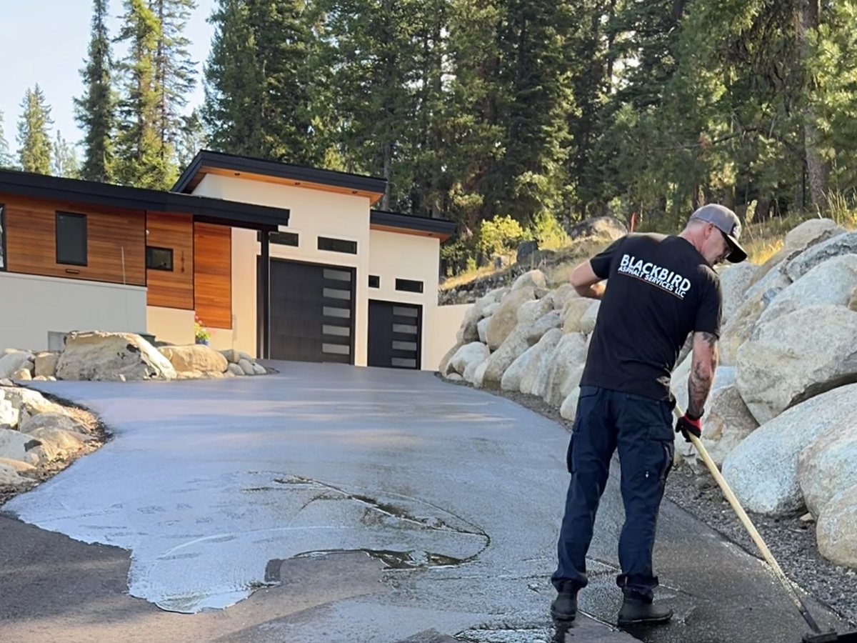 Crew member applying sealcoat to a driveway with a squeegee