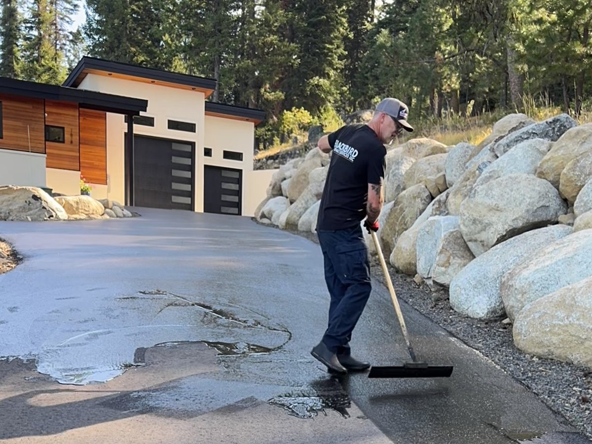 Crew member working sealcoat across a residential driveway