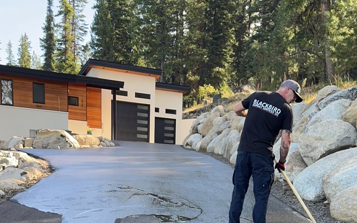 Blackbird Asphalt Services crew member squeegeeing sealcoat onto a residential driveway
